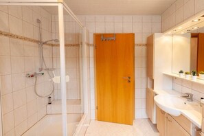Une salle de bain avec une douche, un lavabo et un miroir.