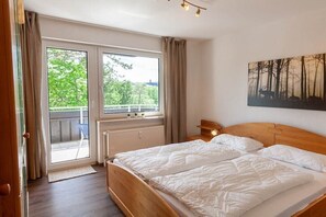 Une chambre avec un lit double, une fenêtre donnant sur un paysage verdoyant et un tableau accroché au mur.