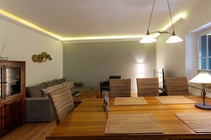 Een eetgedeelte met een houten tafel, geweven placemats en een lamp.