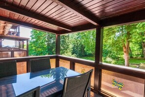 A covered outdoor dining area with a table and chairs, surrounded by wooden beams and glass panels. - Holiday apartment with 3 bedrooms (Braunlage)