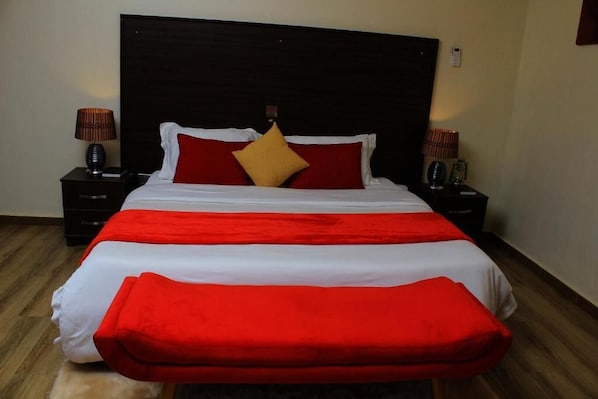 A hotel room with a large bed, two bedside tables, and a headboard.