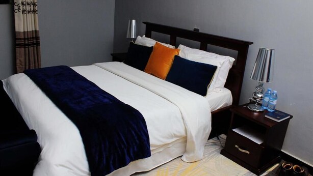 Une chambre d’hôtel avec un lit, des tables de chevet, une lampe et une paire de chaussures.