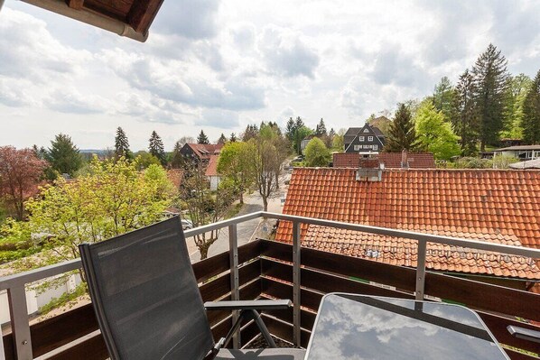 A balcony with a view of a residential area, including houses with red-tiled roofs and trees. - Small spruce tree with balcony (Braunlage)
