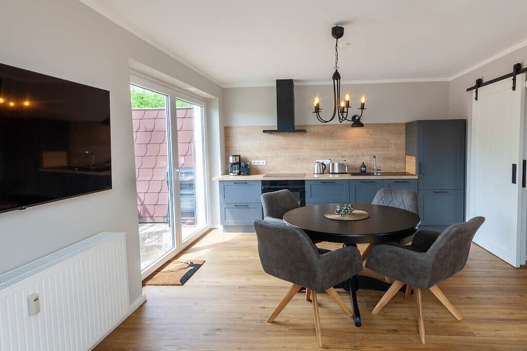 Una cocina moderna con comedor, que incluye un televisor de pantalla plana, un candelabro y un amplio ventanal.