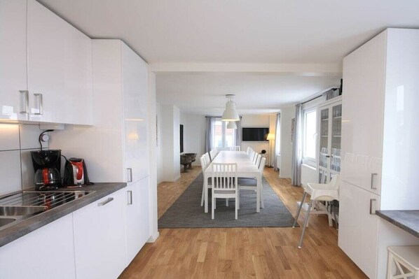 Une cuisine moderne avec des meubles blancs, un coin repas comprenant une table et des chaises, et un plancher en bois.