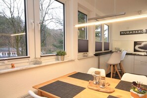 A modern kitchen with a large window, a wooden table, and a countertop with a coffee machine. - Holiday apartment with 1 bedroom (Braunlage)