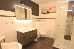 A modern bathroom with a vanity, toilet, and shower. - Holiday apartment with 1 bedroom (Braunlage)