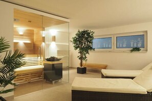 A modern spa room with a glass partition, a massage table, a bench, and a potted plant. - Holiday apartment with 1 bedroom (Braunlage)