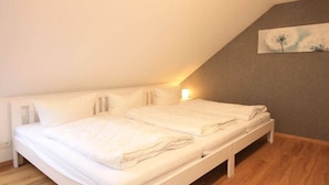 Quarto com cama, mesa de cabeceira e luminária na parede.