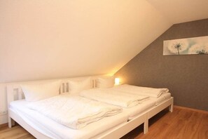 A bedroom with a bed, a nightstand, and a wall-mounted lamp. - Holiday apartment with 1 bedroom (Braunlage)
