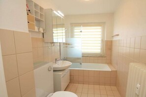Une petite salle de bain comprenant des toilettes, un lavabo et une baignoire.