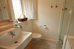 Une salle de bain avec un lavabo blanc, des toilettes et une douche à parois de verre.