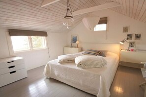 Une chambre à coucher avec un lit, des tables de chevet, une commode et une fenêtre.