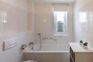 Ein modernes Badezimmer mit einer Badewanne, einer Dusche und einem Fenster.