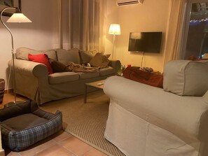 Ein Wohnzimmer mit einer Couch, einem Sessel, einem Couchtisch und einem Fernseher.
