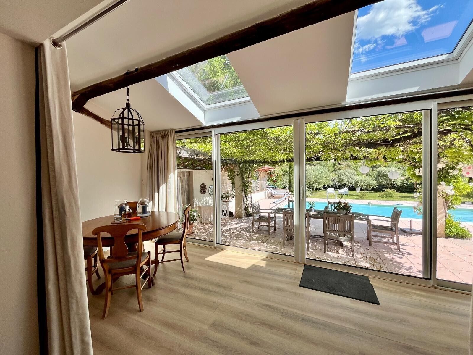 A dining area with a table and chairs, a large sliding glass door leading to a pool and garden.