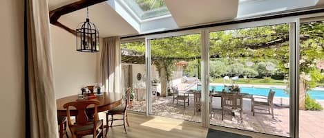 A dining area with a table and chairs, a large sliding glass door leading to a pool and garden.