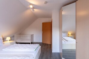 Une chambre à coucher avec un lit, un berceau, une table de chevet et un miroir.