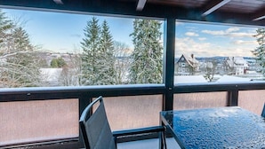 Varanda com vista para árvores e casas cobertas de neve.