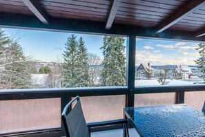 Un balcon donnant sur des arbres et des maisons couverts de neige.