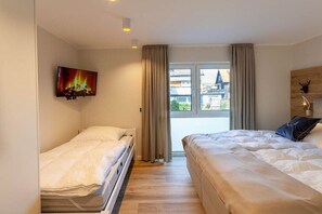 Une chambre d’hôtel avec deux lits, un téléviseur fixé au mur et une vue sur l’extérieur.