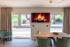 Une pièce avec une cheminée, une table à manger et une vue sur l’extérieur.