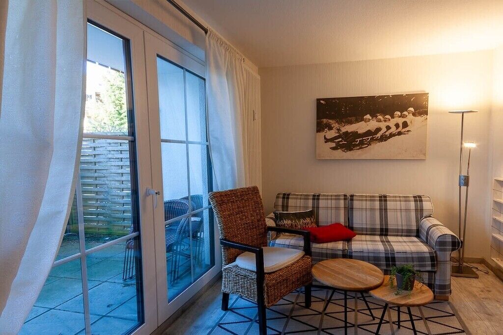 Un salon comprenant un canapé, un fauteuil et une petite table ronde agrémentée d’une plante.