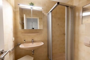 Une salle de bain avec une douche, un lavabo et un miroir.