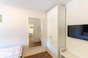 Une chambre à coucher comprenant un lit, une armoire, un téléviseur fixé au mur et un miroir qui reflète la pièce.