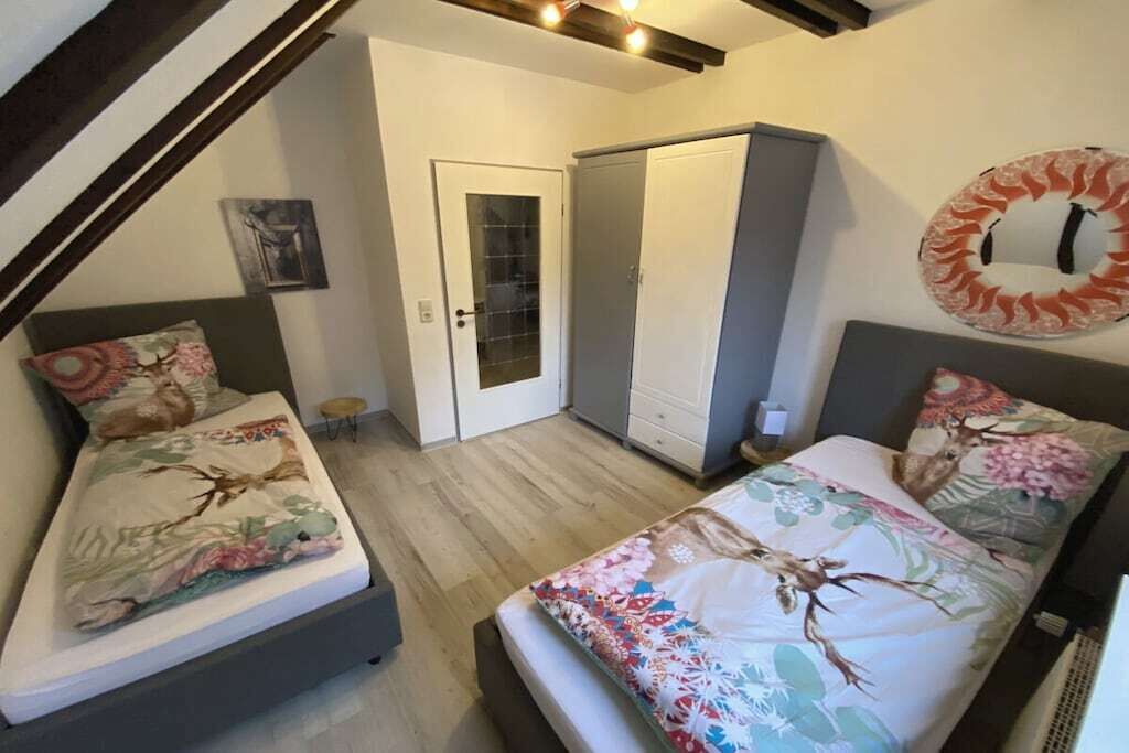 Un dormitorio con dos camas, un armario y una puerta que da a otra habitación.