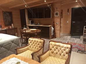 Une pièce confortable comprenant un lit, une table à manger avec des chaises, un coin cuisine et un petit autel.