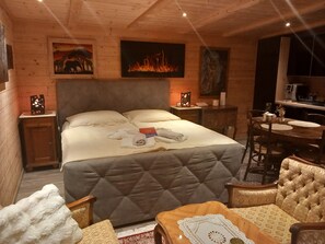 Una habitación acogedora con una cama grande, cabecero de madera, una mesa de comedor y una chimenea.