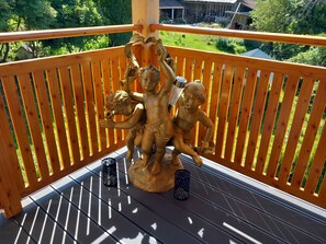Un balcón con baranda de madera, una estatua de querubines y dos candelabros decorativos.