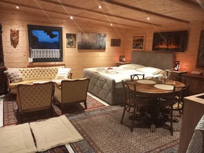 A cozy room with a sofa, a bed, a dining table, and a fireplace.
