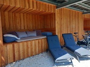 Una cabaña de madera con un banco incorporado y dos sillones de descanso.