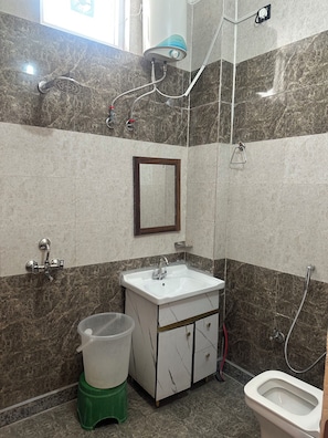 Ein Badezimmer mit Waschbecken, Spiegel, Dusche und Toilette.