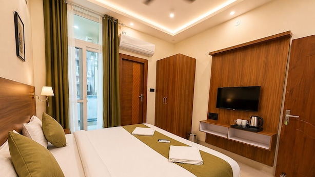 Habitación de hotel con cama, televisor, escritorio y cafetera, y vistas al exterior.