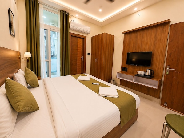 A hotel room with a bed, a TV, a desk with a coffee maker, and a view of the outside.