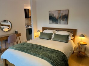 A hotel room with a bed, bedside lamps, a desk, a chair, a mirror, and a painting on the wall. - The Wing is a luxury and peaceful private retreat for two adults. (New Milton)