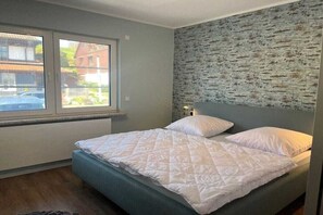 Een slaapkamer met een bed, een raam en een structuurwand.