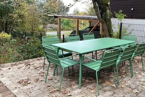 An outdoor patio with a green metal table and chairs, surrounded by trees and a fence. - Holiday apartment with 1 bedroom (Braunlage)