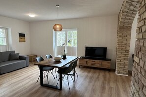 Ein modernes Wohnzimmer mit Essbereich, einem Flachbildfernseher und einem Steingewölbe.