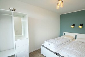 Een slaapkamer met een bed, een witte inbouwkast en een wandlamp.