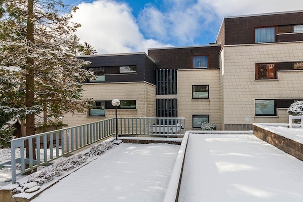 Un bâtiment moderne doté de nombreux balcons, un sol recouvert de neige et un ciel dégagé.