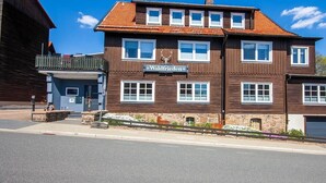 Um edifício de dois andares com uma placa indicando 'Waldfriden' e uma estátua de veado na fachada.