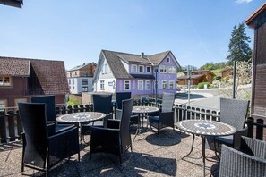 Un espace extérieur aménagé avec des tables et des chaises rondes, offrant une vue sur des maisons aux couleurs vives et un ciel dégagé.