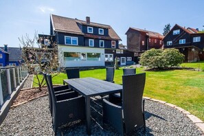 Un quartier résidentiel avec des maisons, une terrasse dotée de mobilier d’extérieur et une pelouse bien entretenue.