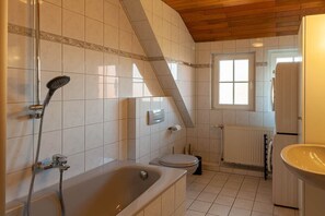Ein Badezimmer mit Badewanne, Dusche, Toilette und Fenster.