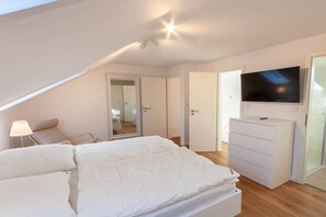 A bedroom with a bed, a dresser, a television, and a door leading to another room. - Eye-catching with a dream view (Braunlage)