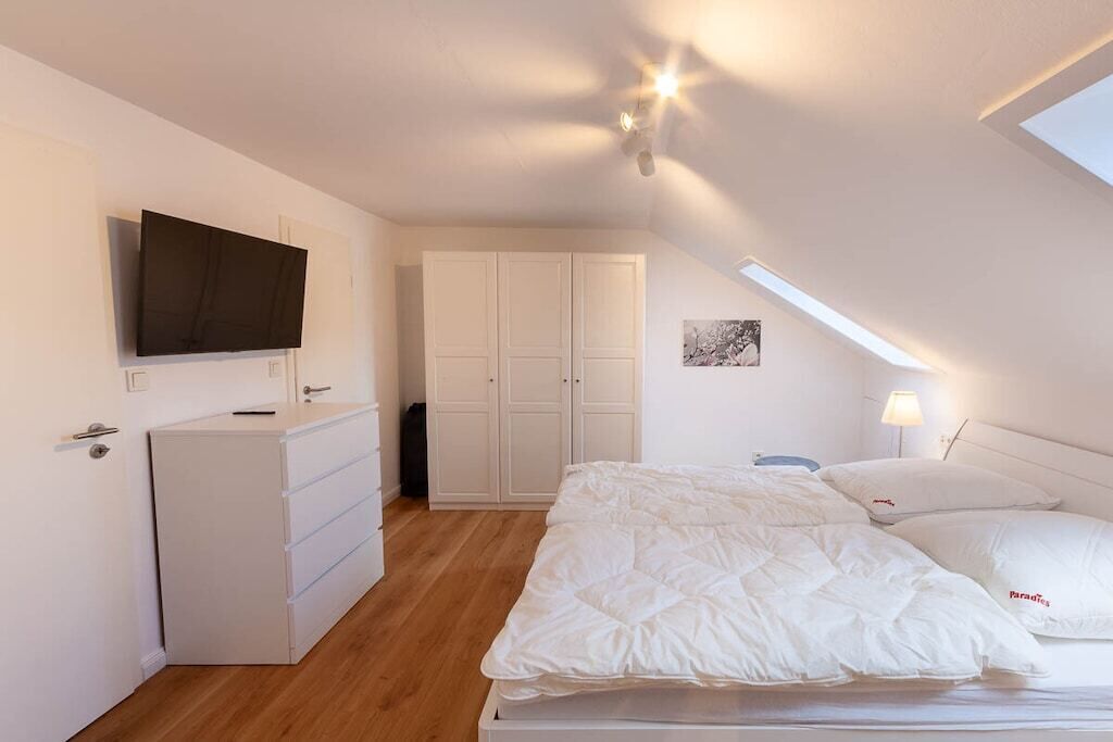 Een slaapkamer met een bed, een dressoir, een televisie en een kledingkast.